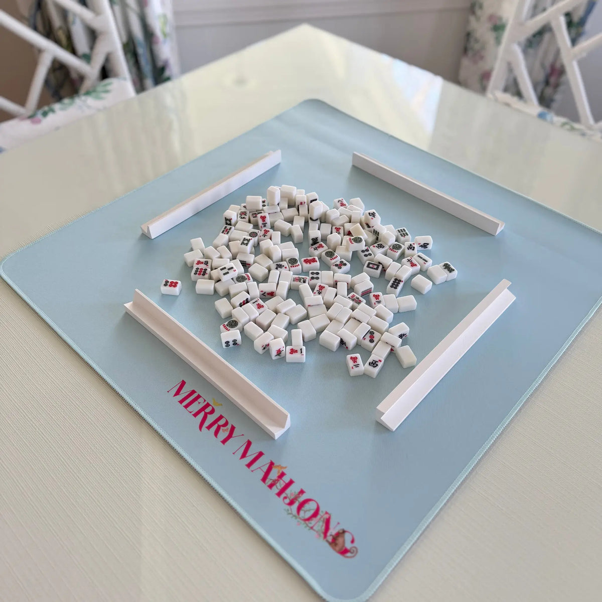 Light blue mini travel Mahjong mat with miniature tiles and white racks set up for play.