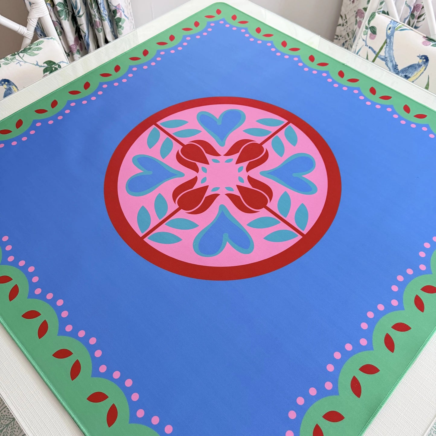 Photograph of a luxury Hearts & Flowers mahjong mat featuring a bright, cheerful floral and holiday-inspired design with vivid azure, gray green, red, and pink tones.