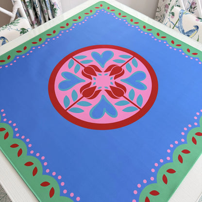Photograph of a luxury Hearts & Flowers mahjong mat featuring a bright, cheerful floral and holiday-inspired design with vivid azure, gray green, red, and pink tones.