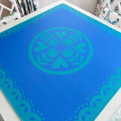 Photograph of the Hearts & Flowers Azure Bloom mahjong mat featuring floral and heart-inspired artwork in calming azure and cyan tones with a clean, modern design.