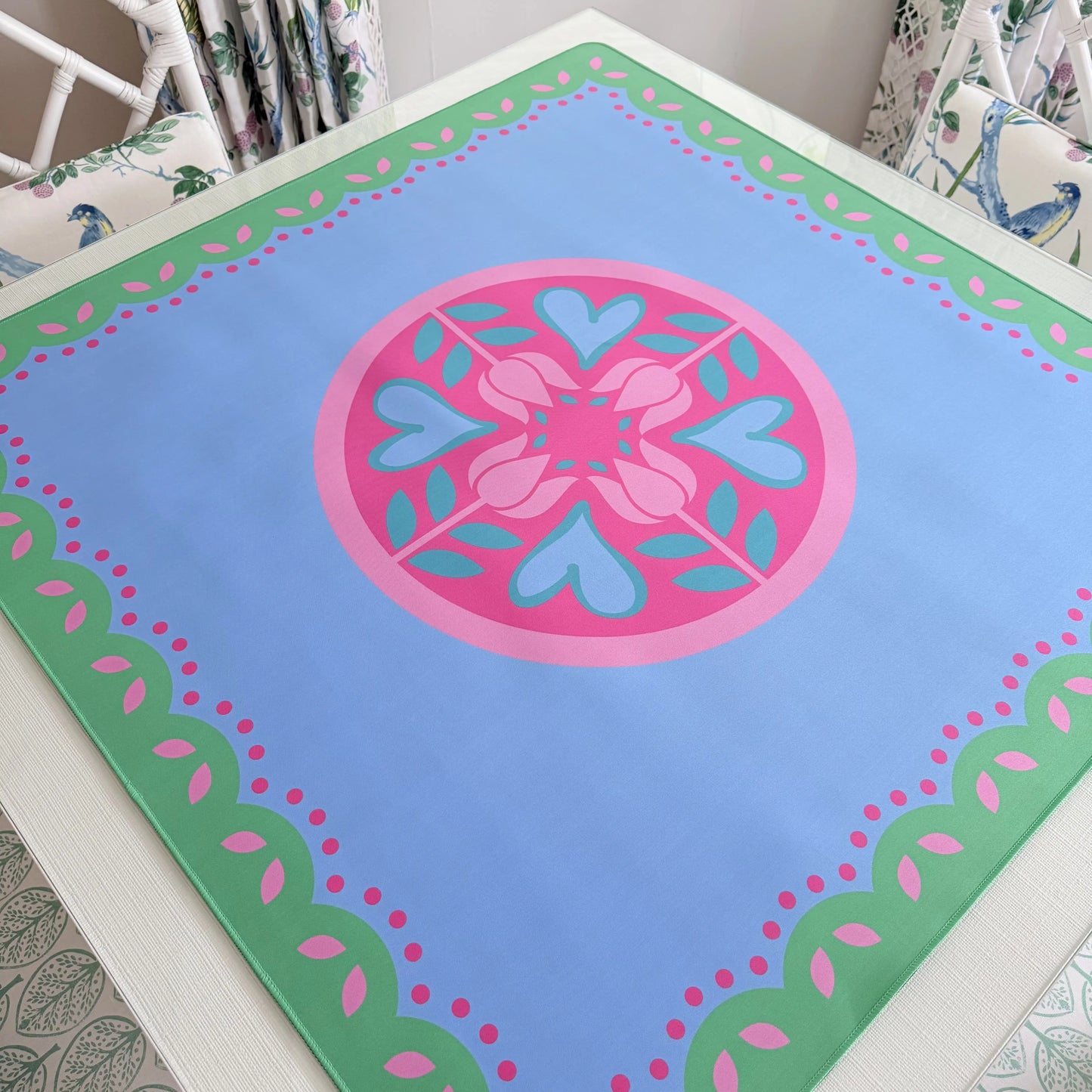 Photograph of the Hearts & Flowers Pastel Garden mahjong mat featuring floral and heart-inspired artwork in pastel azure, green, vivid magenta, light magenta, and cyan tones.