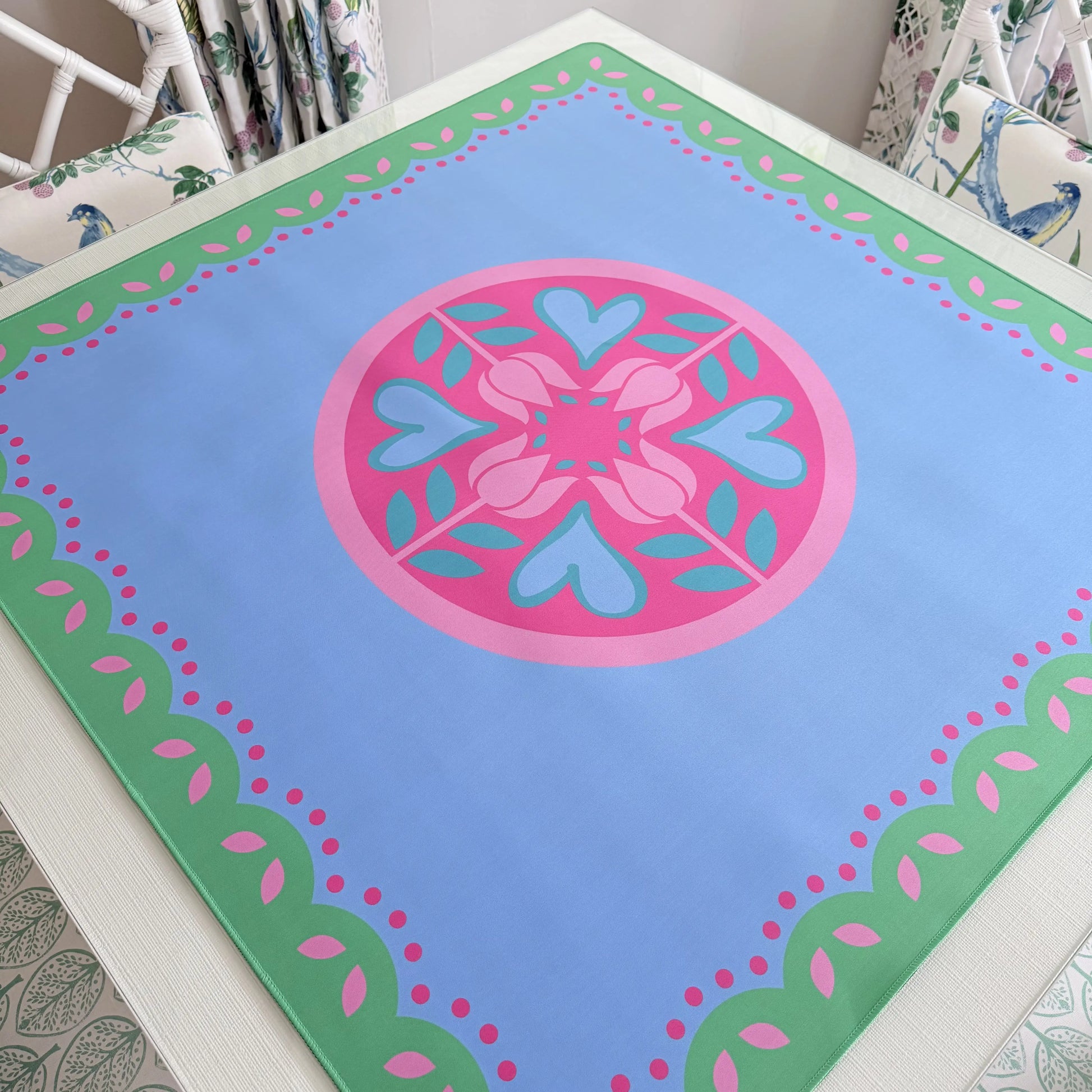 Photograph of the Hearts & Flowers Pastel Garden mahjong mat featuring floral and heart-inspired artwork in pastel azure, green, vivid magenta, light magenta, and cyan tones.
