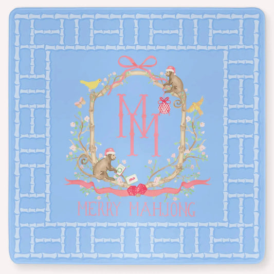 The Bamboo Blossom Christmas Edition Mahjong Mat featuring a festive bamboo lattice border design, monkeys with Christmas hats, ornaments, bows, birds, flowers and leaves with the Merry Mahjong Logo.