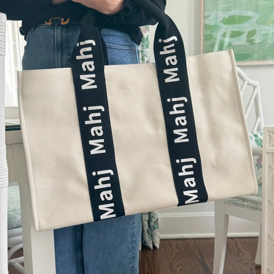 Black oversized Mahjong tote bag being carried by its handles.