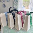 Four oversized Mahjong tote bags in Kelly Green, Hot Pink, Black, and Light Blue standing upright side by side.