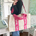 Model carrying a hot pink oversized Mahjong tote bag with MAHJ shoulder straps.