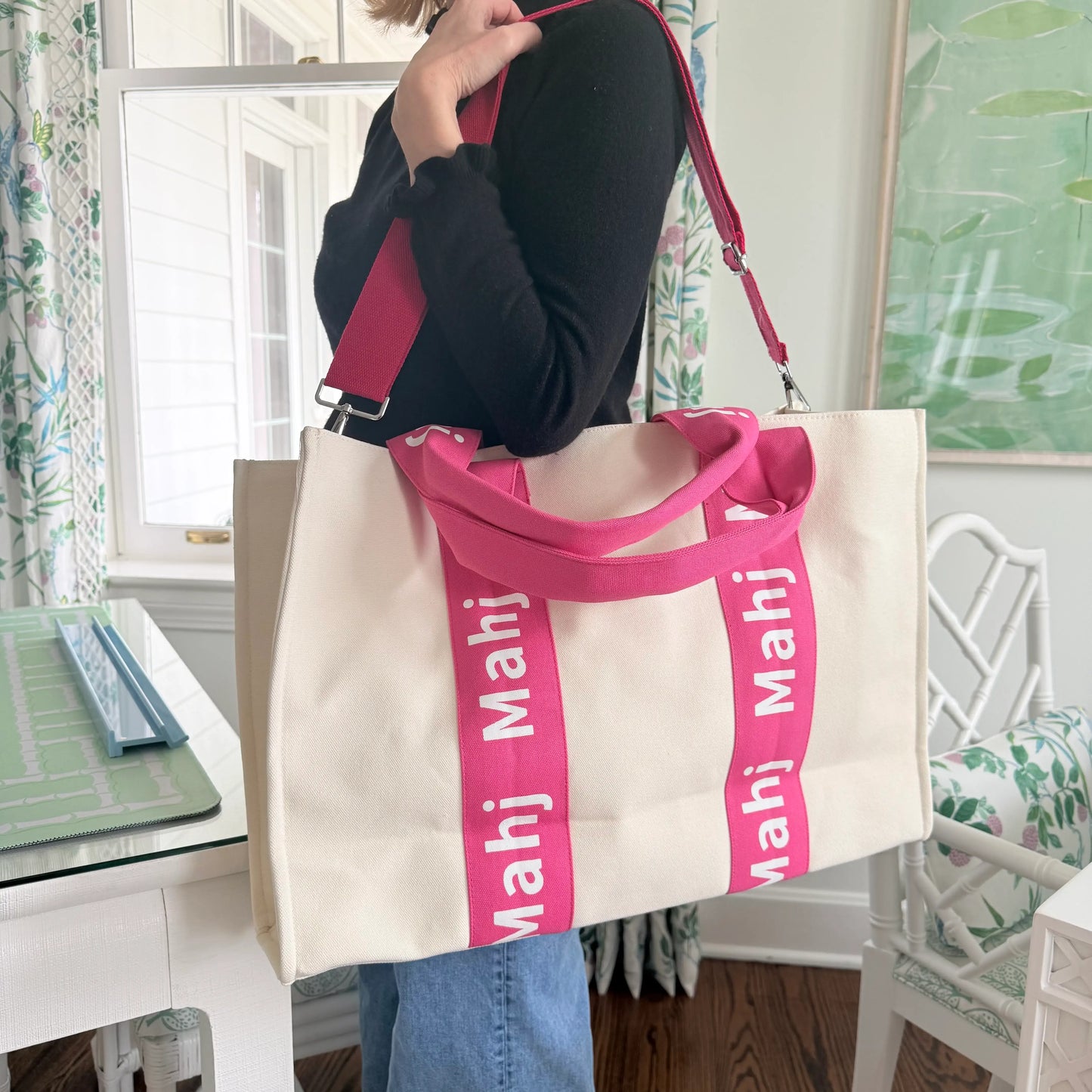 Model carrying a hot pink oversized Mahjong tote bag with MAHJ shoulder straps.