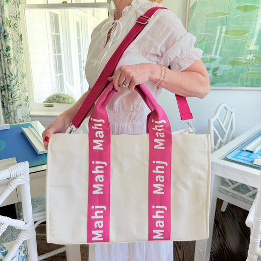 Hot pink oversized Mahjong tote bag being carried by its straps around the model's shoulders and showcasing the handle.