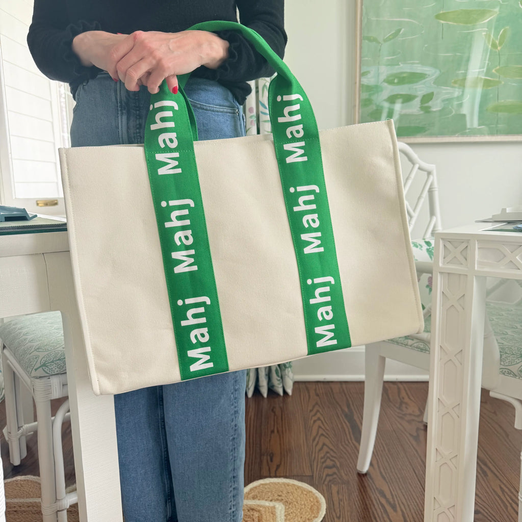 Person carrying a green oversized Mahjong tote bag by the handles to showcase its size and structured design.
