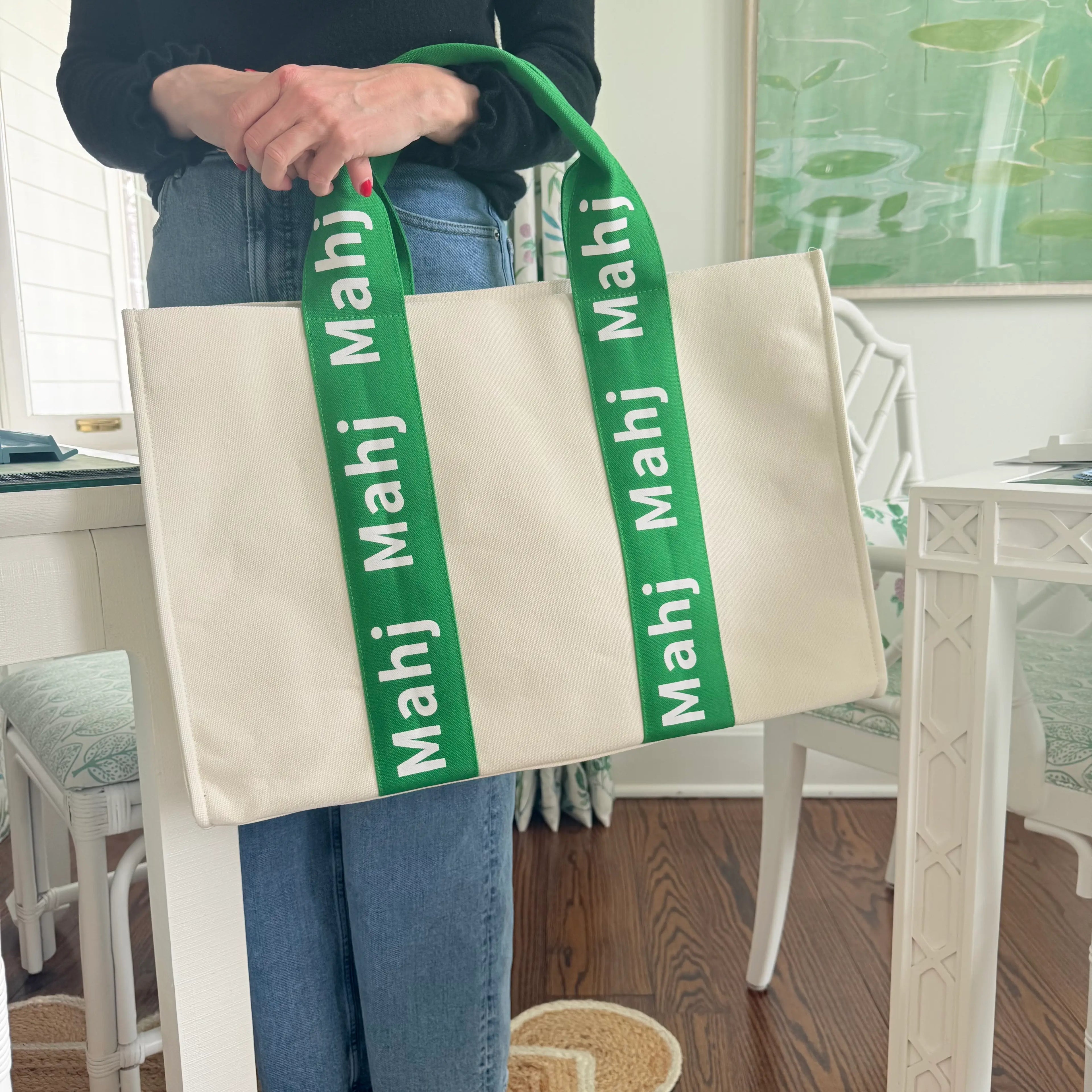 Person carrying a green oversized Mahjong tote bag by the handles to showcase its size and structured design.