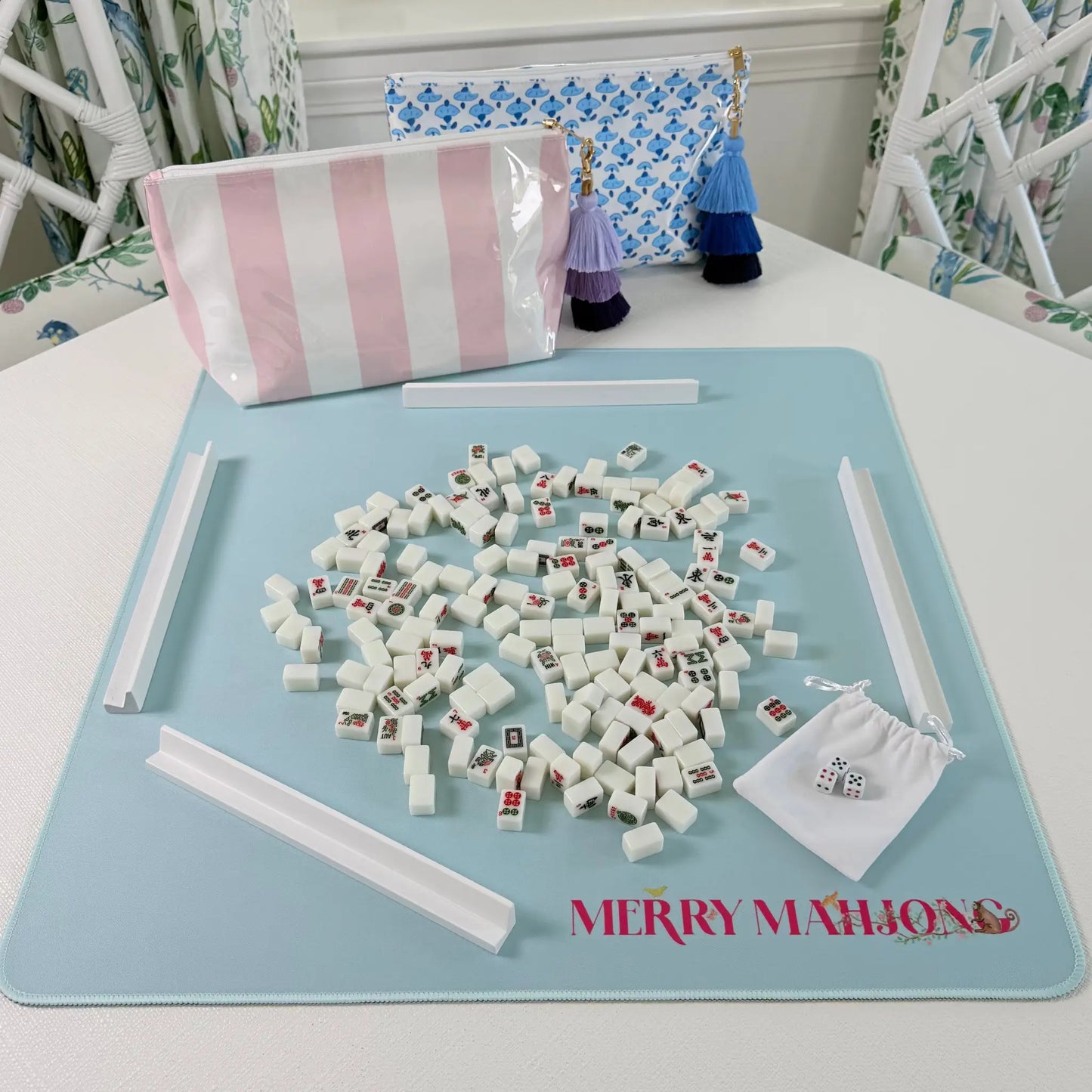 Mini Mahjong travel set in play with miniature tiles, white racks, pink striped tile bag, blue blockprint bag, and light blue travel mat.