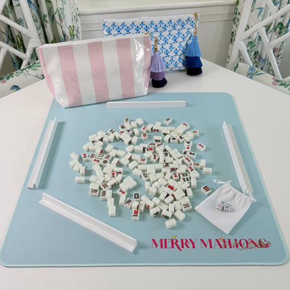 Mini Mahjong travel set in play with miniature tiles, white racks, pink striped tile bag, blue blockprint bag, and light blue travel mat.