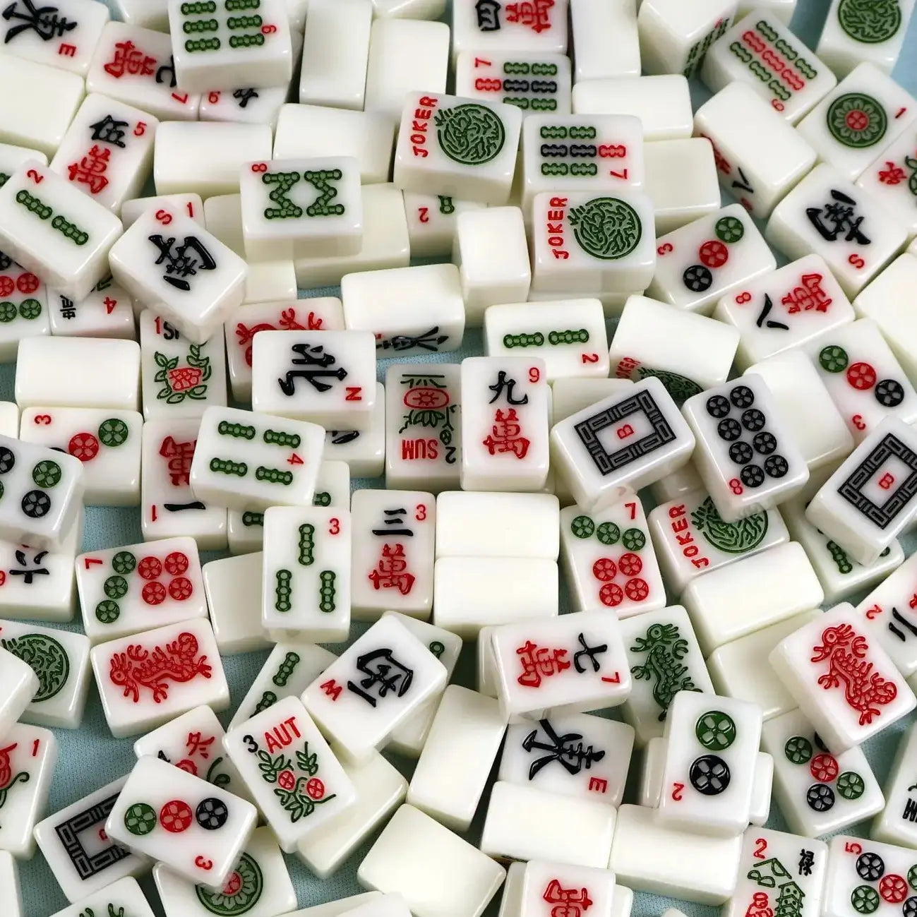 Close-up of miniature Mahjong tiles from a mini travel set, showing the small tile size and detailed designs.
