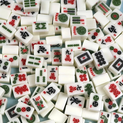 Close-up of miniature Mahjong tiles from a mini travel set, showing the small tile size and detailed designs.