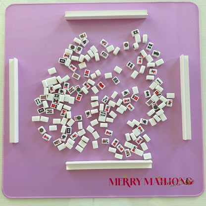 Purple mini travel Mahjong mat with miniature tiles and white racks set up for play.