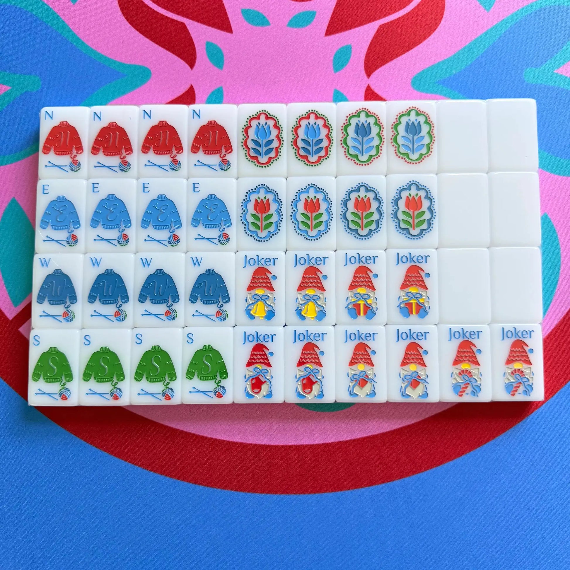 A showcase of the Scandinavian Christmas Red & Green Mahjong Tile collection's winds and jokers in their packaging on the Peppermint Bloom Mahjong Mat.