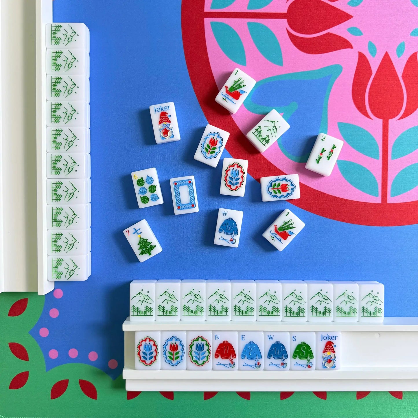 A showcase of the Scandinavian Christmas Red & Green Mahjong Tile collection seen in play on white wooden mahjong racks on the Peppermint Bloom Mahjong Mat.