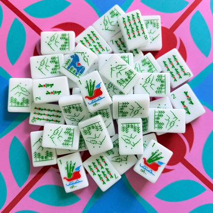 A pile of The Scandinavian Christmas Red & Green Mahjong Tile collection's bam tiles showcased on top of the Peppermint Bloom Mahjong Mat.