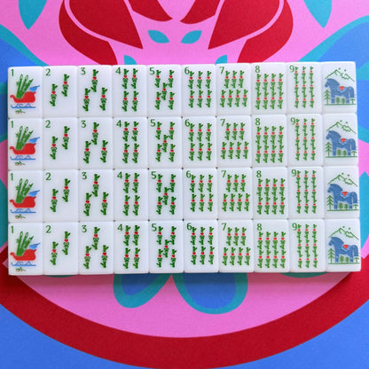 A showcase of the Scandinavian Christmas Red & Green Mahjong Tile collection's bams in their packaging on the Peppermint Bloom Mahjong Mat.