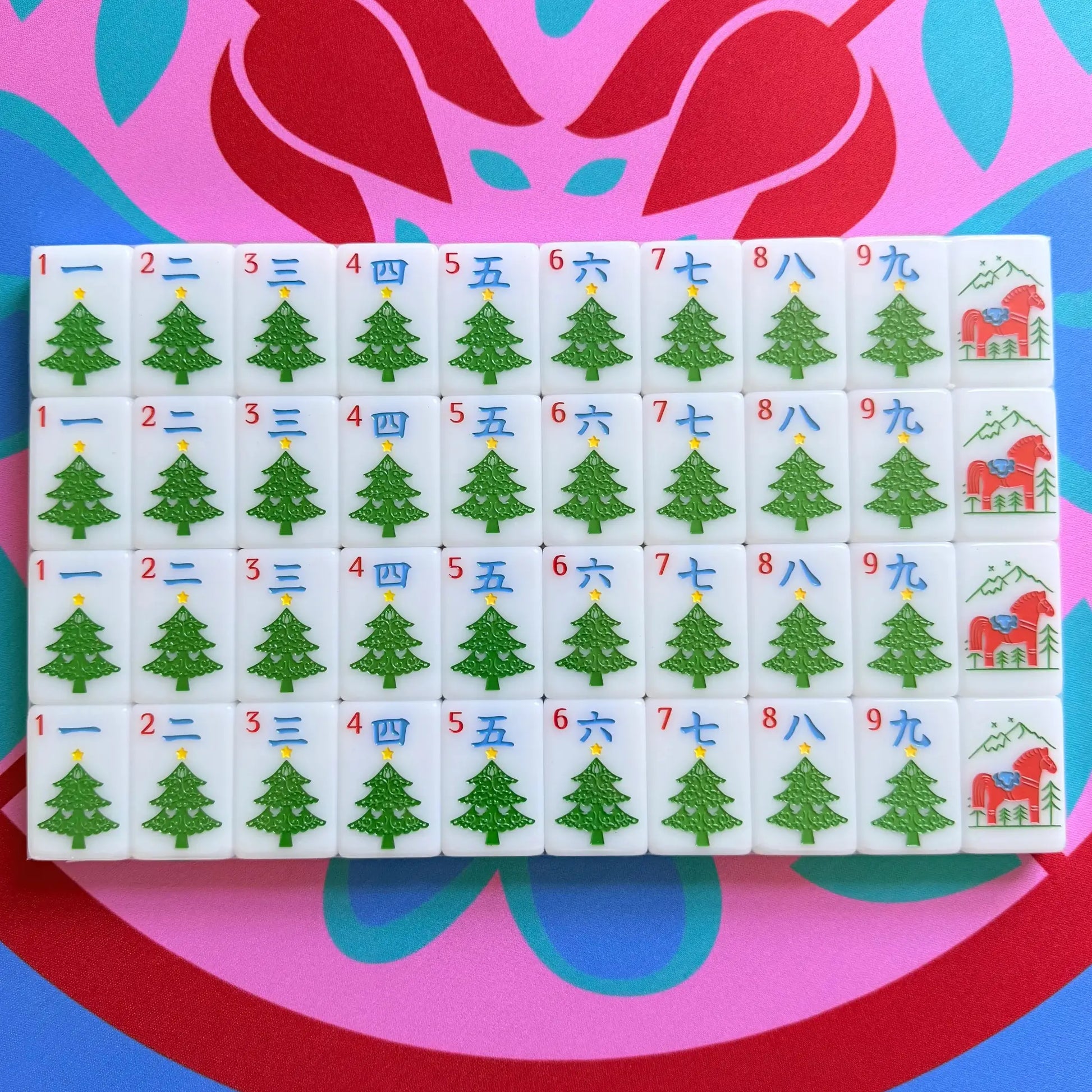 A showcase of the Scandinavian Christmas Red & Green Mahjong Tile collection's cracks in their packaging on the Peppermint Bloom Mahjong Mat.