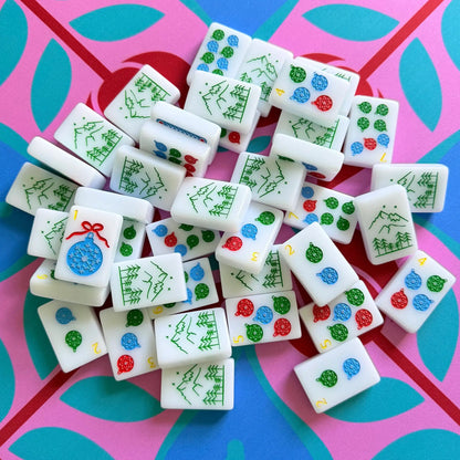 A pile of The Scandinavian Christmas Red & Green Mahjong Tile collection's dot tiles showcased on top of the Peppermint Bloom Mahjong Mat.