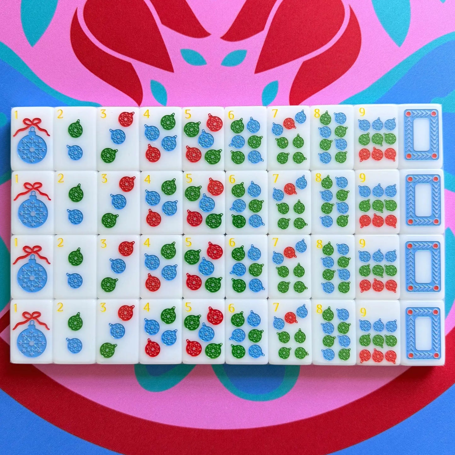 A showcase of the Scandinavian Christmas Red & Green Mahjong Tile collection's dots in their packaging on the Peppermint Bloom Mahjong Mat.