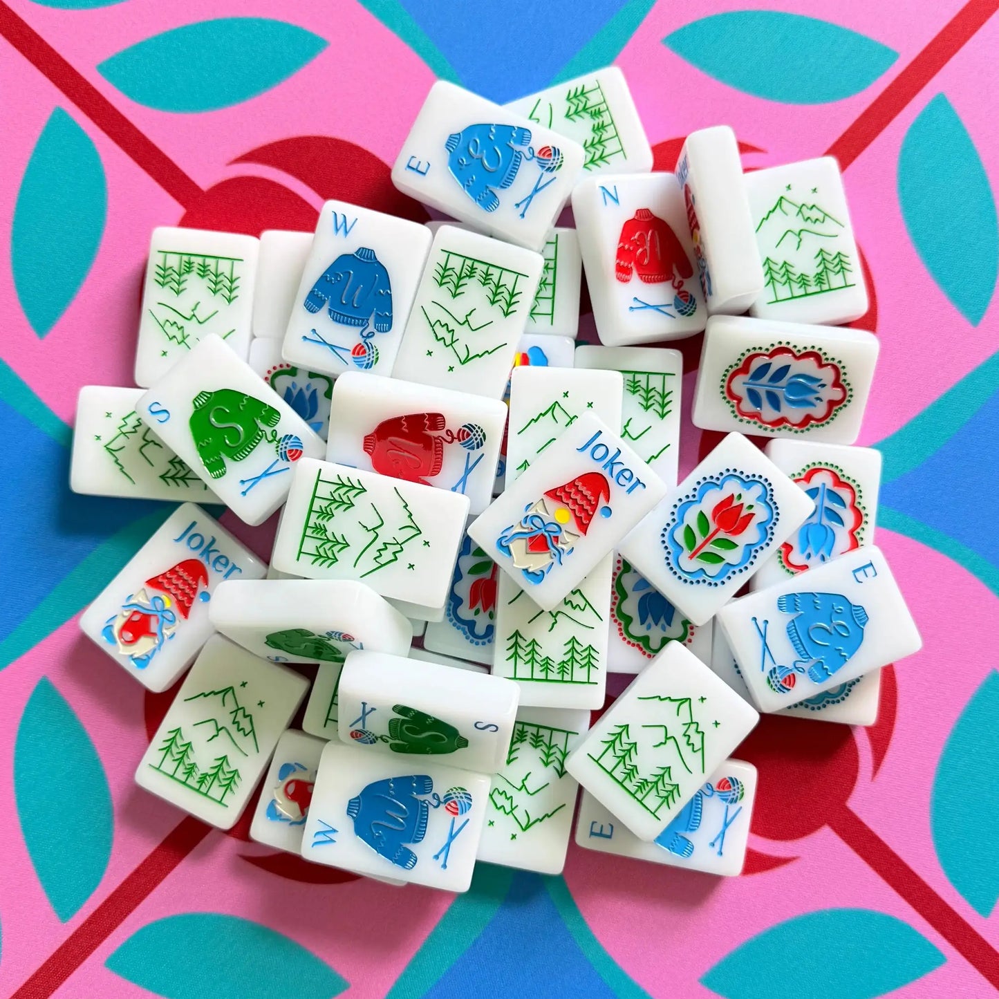 A pile of The Scandinavian Christmas Red & Green Mahjong Tile collection's joker and wind tiles showcased on top of the Peppermint Bloom Mahjong Mat.