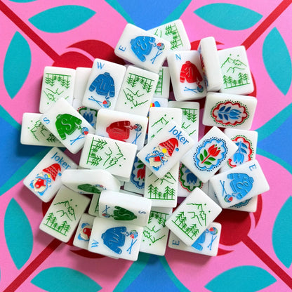 A pile of The Scandinavian Christmas Red & Green Mahjong Tile collection's joker and wind tiles showcased on top of the Peppermint Bloom Mahjong Mat.
