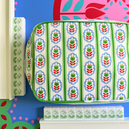A showcase of the Scandinavian Christmas Red & Green Mahjong Tile collection with the backs of the tiles highlighted resting against white wooden racks with a matching bag on the Peppermint Bloom Mahjong Mat.